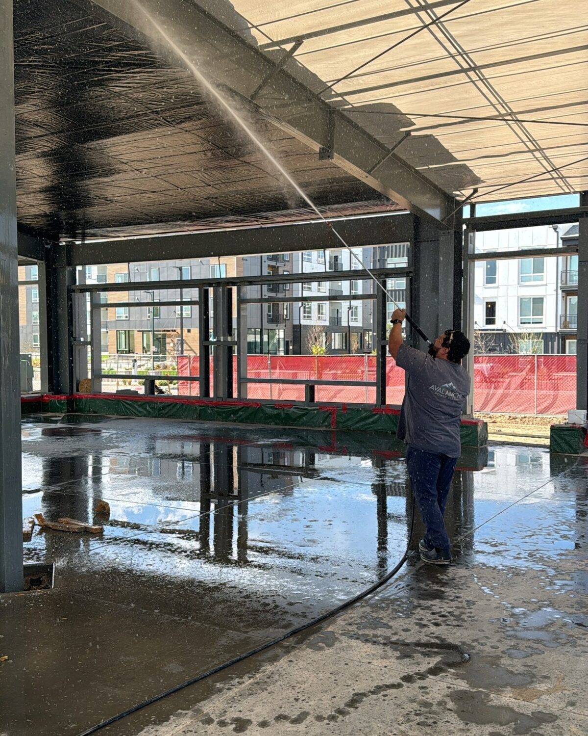 Avalanche technician pressure washing a commercial building canopy
