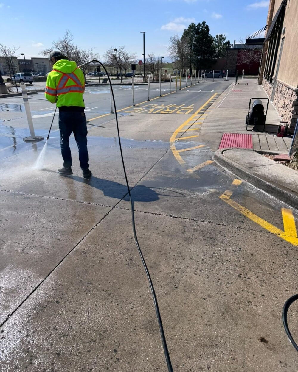Avalanche technician pressure washing a commercial drive-thru lane