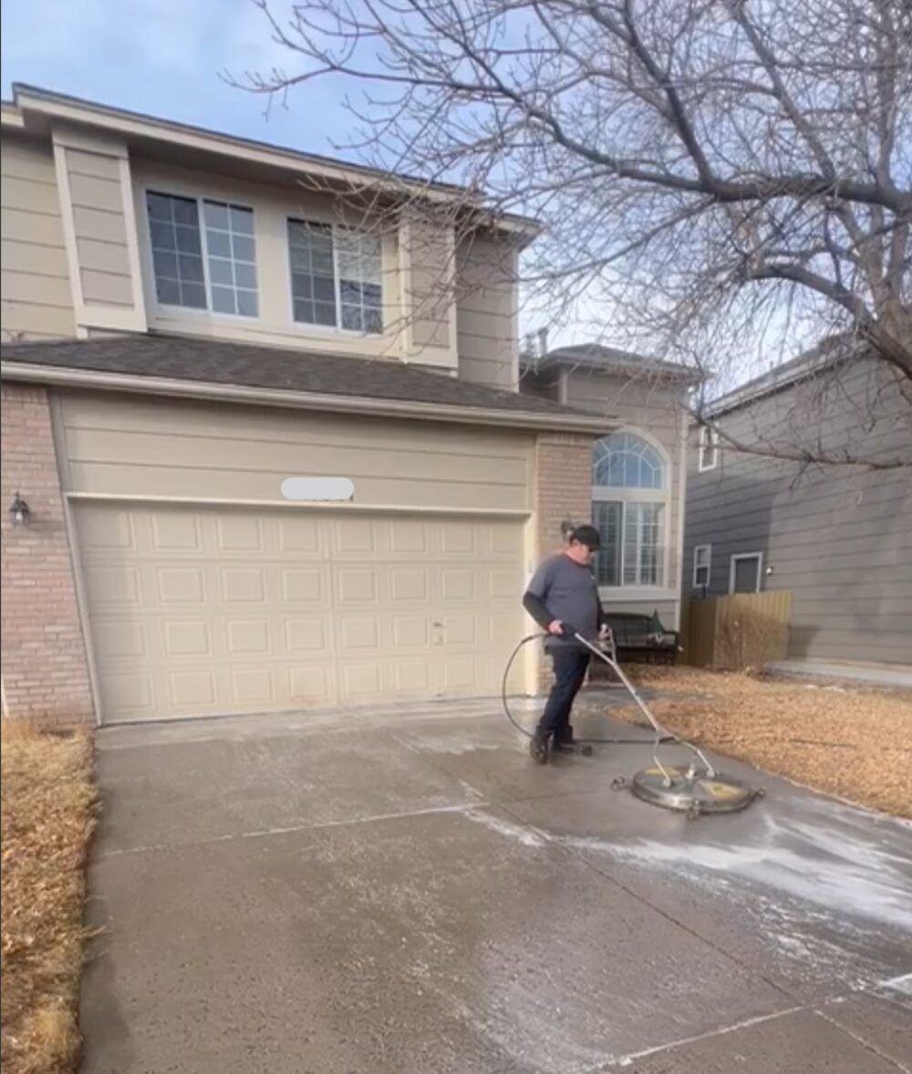 Avalanche technician using a surface cleaner on a residential driveway