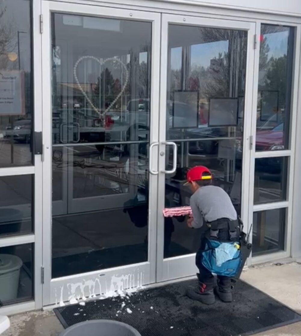 Avalanche technician washing storefront glass doors